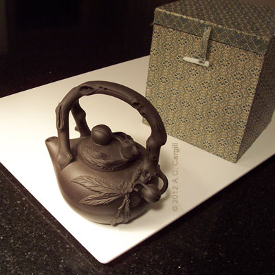 A peach-design Yixing teapot with brocade covered storage box A peach-design Yixing teapot with brocade covered storage box